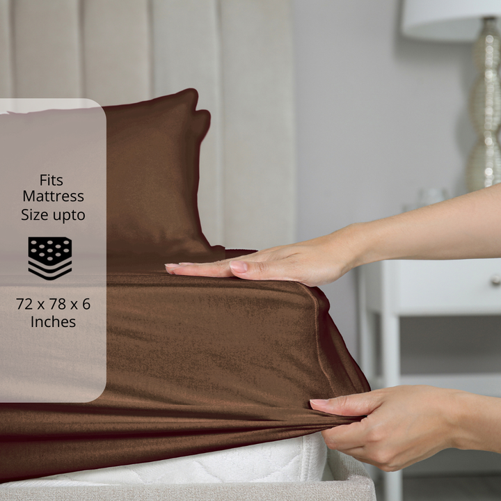 Coffee Brown bedsheet being stretched over mattress corner with size label showing fits mattress size up to 72 x 78 x 6 inches.  