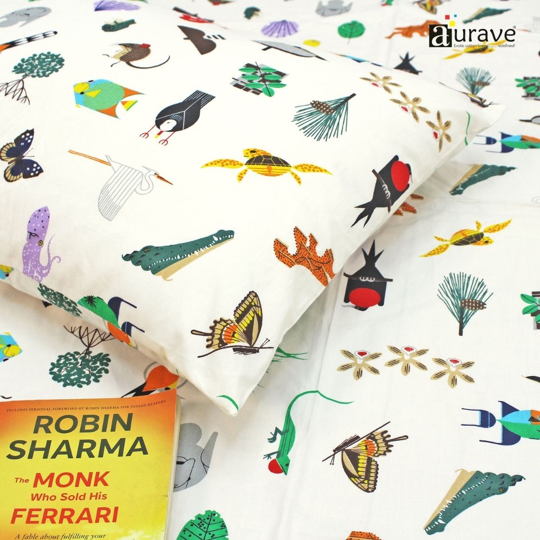 Close-up detail of a soft 210 TC pure cotton kids pillowcase and white bedsheet showing printed butterflies, crocodiles, and turtles, styled with a book.