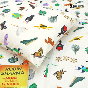 Close-up detail of a soft 210 TC pure cotton kids pillowcase and white bedsheet showing printed butterflies, crocodiles, and turtles, styled with a book.