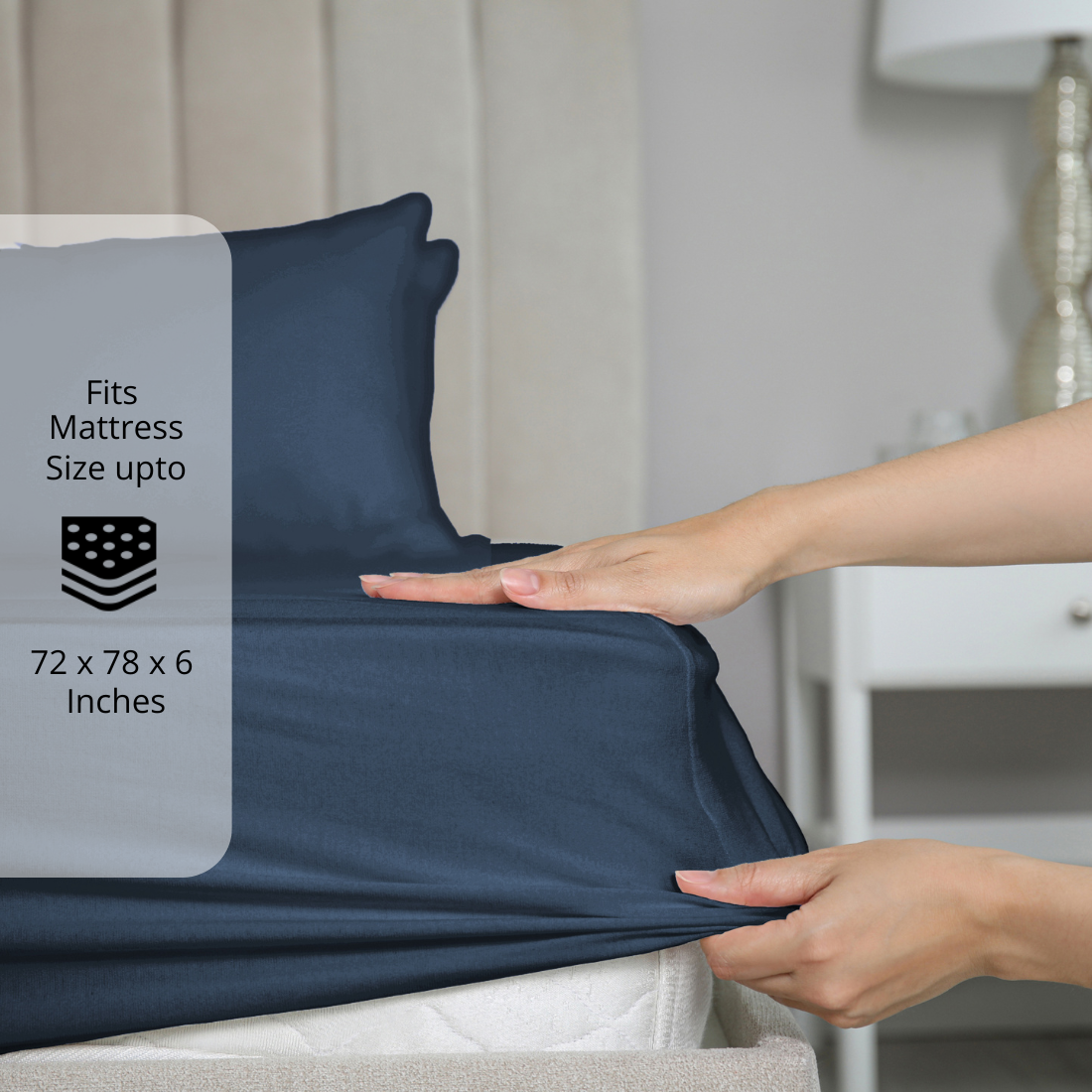 Navy Blue fitted bedsheet being stretched over mattress corner with size label showing fits mattress size up to 72 x 78 x 6 inches.  