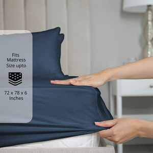 Navy Blue fitted bedsheet being stretched over mattress corner with size label showing fits mattress size up to 72 x 78 x 6 inches.  
