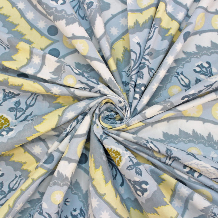 Cotton blend bedsheet fabric with blue and beige floral print, swirl folded close-up view
