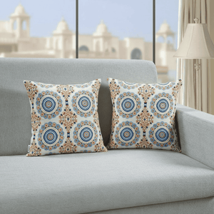 Decorative pillows with circular patterns on a gray sofa in a room with a blurred architectural background.