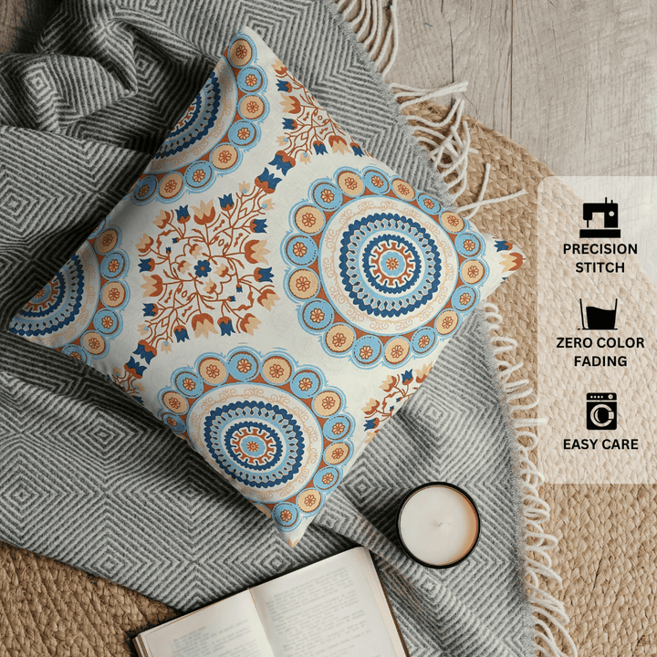 Decorative pillow with intricate patterns on a textured surface with a candle and book.