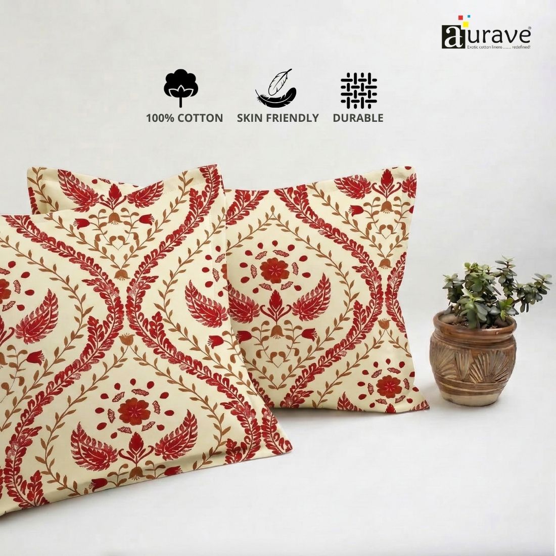 Neatly stacked AURAVE cotton pillow covers showcasing a traditional maroon red floral motif on a cream off-white base.
