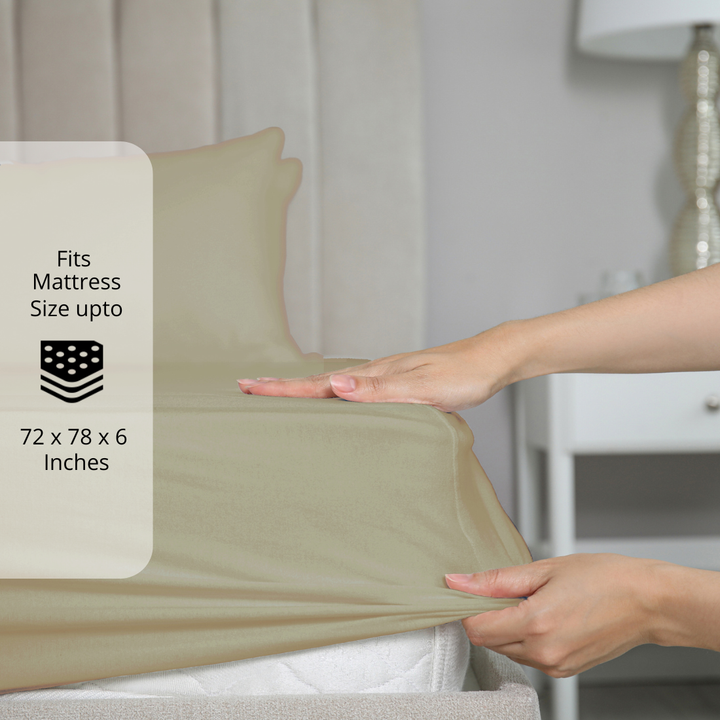 Taupe bedsheet being stretched over mattress corner with size label showing fits mattress size up to 72 x 78 x 6 inches.  